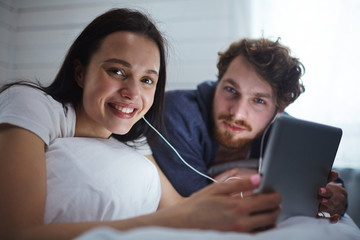 Young sleepless couple watching movie online in touchpad