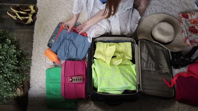 Female hands packing clothes into travel bag