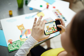 Schoolchild photographing her picture of cat