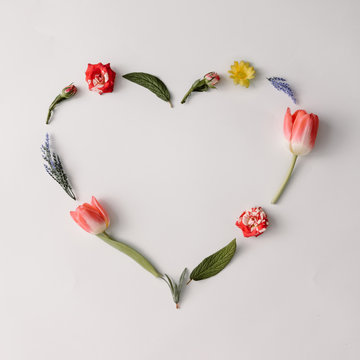 Heart shape made of colorful spring flowers and leaves. Flat lay. Love concept.