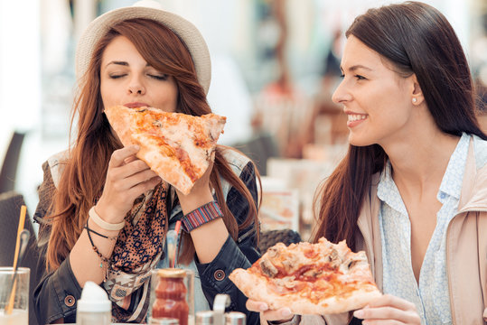 Portrait of two young women eating pizza