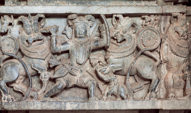 Hunter kills lions on the hunt, carved sculpture on historical wall of indian stone temple Hoysaleswara, India. Temple was built in 1150 by king of Hoysala Empire, now karnataka state.