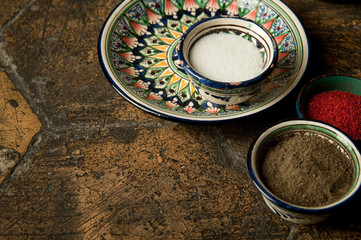Obraz na płótnie Canvas eastern spices in cups on an old worn paving stone. oriental spices on decorative old tiles