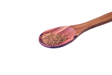 Fenugreek seeds on a brass spoon isolated on a white background.
