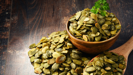 Composition with bowl of pumpkin seeds on wooden table