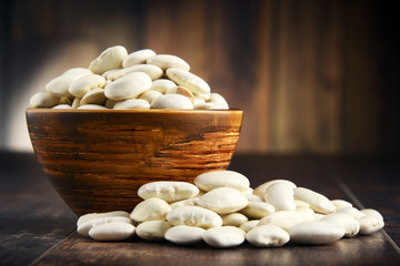 Composition with bowl of white beans on wooden table