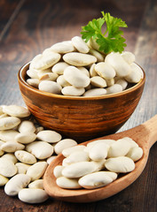 Composition with bowl of white beans on wooden table