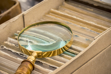 Antique golden magnifying glass lies on a box of photographs.