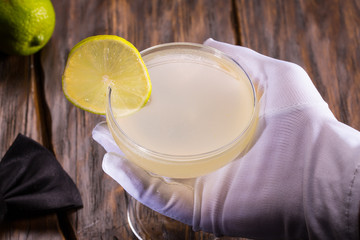 Cocktail with tequila Margarita. The bartender serves a glass with tequila. Tequila, orange liqueur, lemon juice, strawberry or raspberry at choice