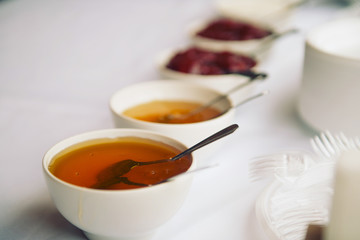 Ceramic bowl with honey and strawberry jam on white background
