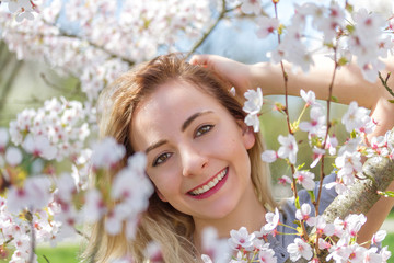 Obraz premium Beautiful happy young woman in a flowering spring garden