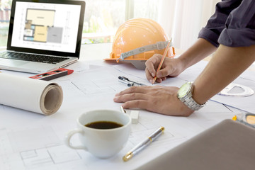 Interior designer discussing data and digital tablet and computer laptop with business document and graphics design diagram on wooden desk as concept