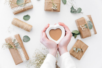 Mothers day concept. Kids hand holding heart over background with gift and hanmsde decorations. Flat lay 