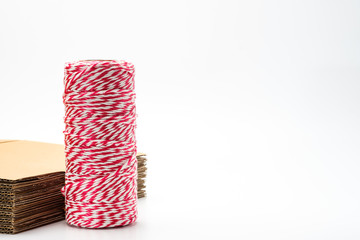 roll of Twine Red and White Stripes Cotton String close to stack of corrugated cardboard box isolated on white background