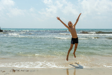 Boy jumps in the air on the background of the sea