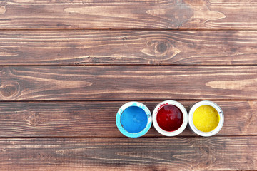 Red yellow and blue paint in jars on a brown wooden stand