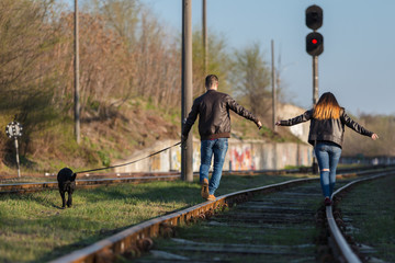 Loving couple with a dog in railway track. The view from the back
