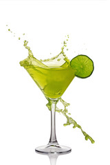 Splash in glass of green alcoholic cocktail drink with lime