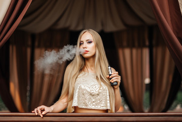 Sexy girl smokes electronic cigarette. The model vaper vaping a vaporizer. Vaping.