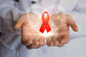 Ribbon for the fight against AIDS and heart symbol in the hands.