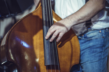 A happy European male musician with a double bass. A middle-aged man wearing glasses.