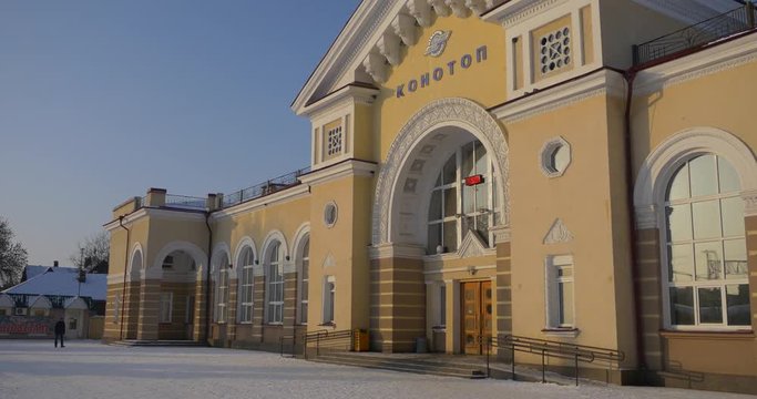 a Fairy Tale Looking Railway Station in Konotop Town, With Yellow Walls, Half Round Windows, and Fir Trees, Growing Nearby in Winter