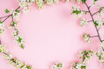 Round frame of spring white flowers on pink background. Flat lay, top view.
