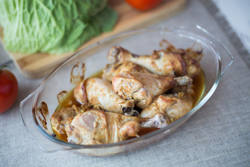 The chicken leg baked in an oven on a glass plate on a gray background