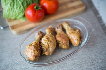 The chicken leg baked in an oven on a glass plate on a gray background