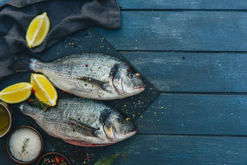 Dorado fish with lemon and spices on a wooden board
