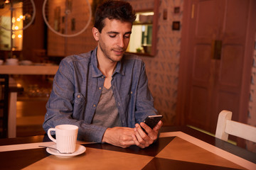 Young man reading message in restaurant