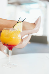Legs with heels and cocktail. Summer luxury concept. 