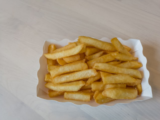 French fries in a paper box on wooden table background
