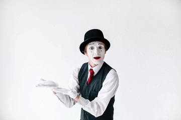 Mime in black hat and red tie holds his hands up