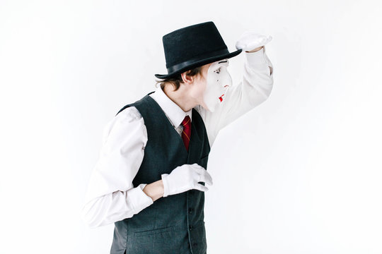 Funny mime in black hat looks far way on white background