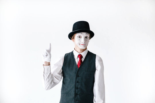 Funny mime in black hat holds his finger up