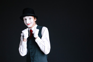 Bashful mime stands on black background