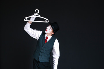 Obraz premium Mime holds hanger in his arm
