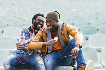 Two black race friends having fun with mobile. - Powered by Adobe