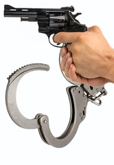 Gun in hand against the background of police handcuffs.