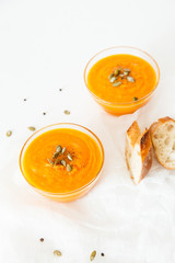 Two plates of pumpkin soup with seeds on a white background with space for your text.
