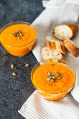 Two plates of pumpkin soup with seeds on a black background with space for your text.