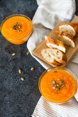 Two plates of pumpkin soup with seeds on a black background with space for your text.