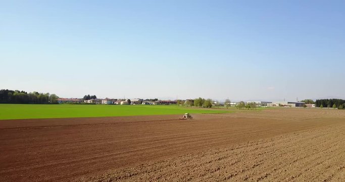 Trattore che ara i campi, vista aerea di un campo arato ed un trattore che semina. Agricoltura e coltivazione, campagna