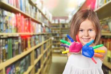 Happy looking kid playing with paints in his fingers.