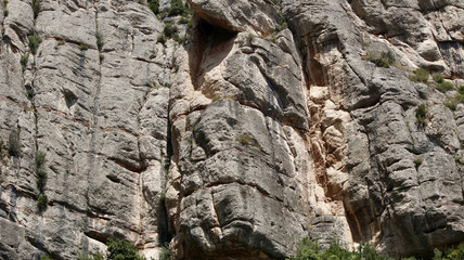 A weathered rocky mountain vertical wall with brown and yellow stones
