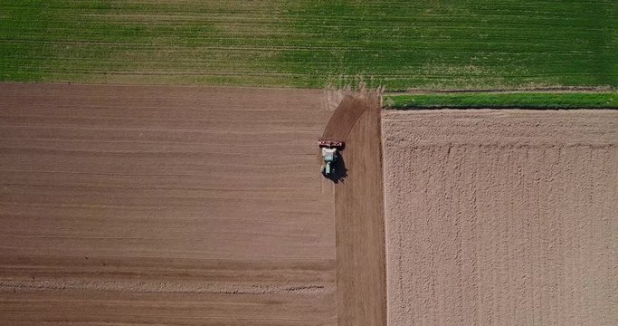 Trattore che ara i campi, vista aerea di un campo arato ed un trattore che semina. Agricoltura e coltivazione, campagna