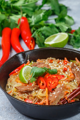 Starch (rice, potatoes) noodles with beef and vegetables - bell peppers, carrots, zucchini, sesame seeds, lime, chili, cilantro and soy sauce. A delicious dinner in the Asian style