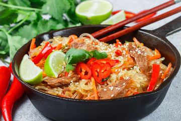 Starch (rice, potatoes) noodles with beef and vegetables - bell peppers, carrots, zucchini, sesame seeds, lime, chili, cilantro and soy sauce. A delicious dinner in the Asian style