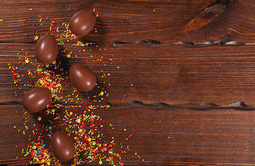 Naklejka premium Delicious chocolate Easter bunny and eggs on wooden background